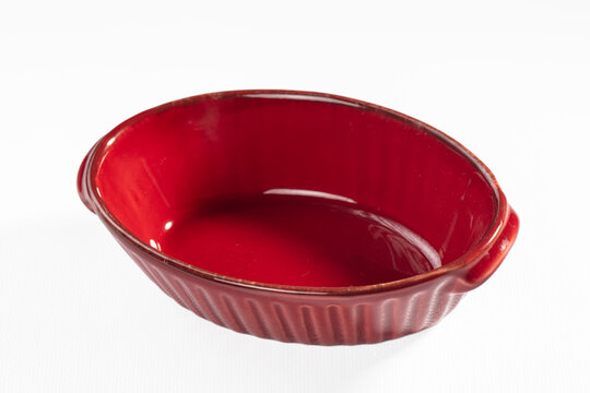 Red ceramic baking dish with ribbed exterior and glossy finish on white background