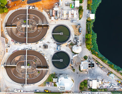Aerial view of the Wastewater Treatment Institute featuring large circular sedimentation tanks and industrial infrastructure situated near a pond in Ramat Hasharon, Tel Aviv District, Israel.