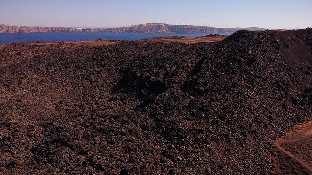 Spectacular drone aerial footage orbiting the Tholos Naftilos volcano on Nea Kameni, highlighting the vast water-filled caldera of Santorini island, Greece.