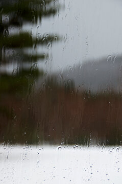 water dripping down window looking out at snow storm in Adirondack mountains new york