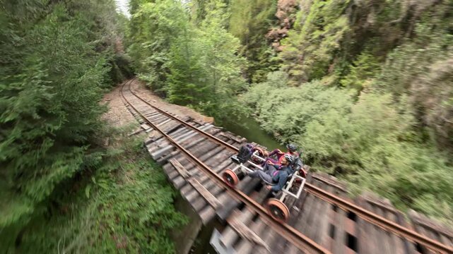 Couple enjoys a ride on an electric railbike along old railroad tracks through a redwood forest near Mendocino in Fort Bragg