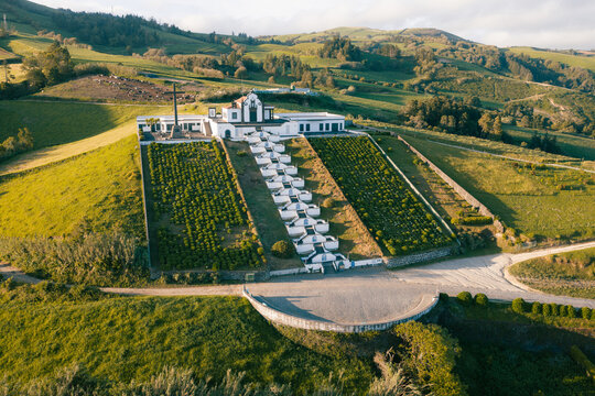 Vila Franca do Campo, Portugal - 05 June 2026: Aerial view of the Ermida de Nossa Senhora da Paz chapel featuring a distinctive tiled staircase and a large stone cross on a green hill.