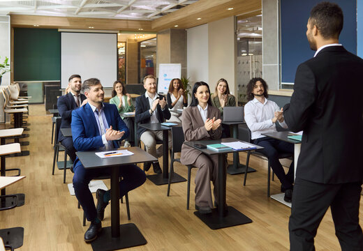 Business team audience applause for seminar speaker. Corporate professionals celebrate a successful training session in a modern office classroom. Clear leadership and strong teamwork concept.