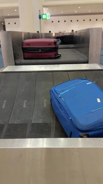 Tracking luggage moving along airport baggage carousel, with suitcases arriving for passengers after flight in modern international terminal, shot handheld. vertical video. High quality 4k footage