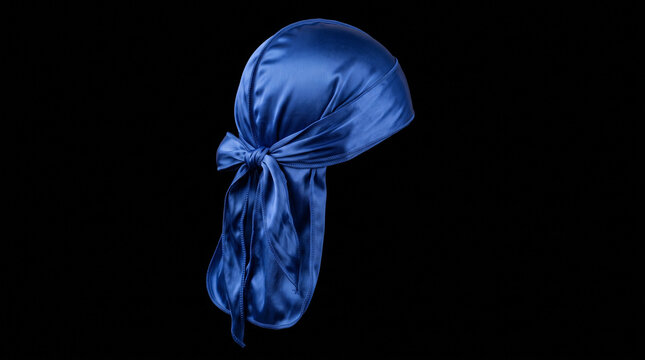 A bright blue silky durag head wrap tied with a knot isolated on black background with against solid black blue satin fabric shiny blue maintenance fashionable