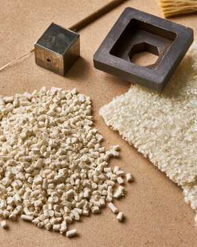 Raw plastic pellets and carpet sample on brown background