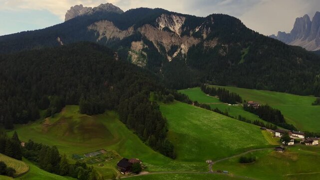 serene rural landscape with green fields and scattered houses, wide-angle shot of mountains in the distance, nature travel background with brown soil and stone elements.