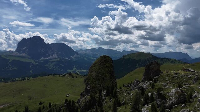 View of beautiful landscape in the Alps with fresh green meadows and mountain tops in the background on a sunny day with blue sky and clouds in summertime. Alpe di Cisles, Seceda Ridgeline, Dolomiti ,