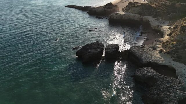Rocky coastline showing visible action, in ocean and rocky cliffs, with rocks, ocean waves, from a aerial perspective, with blue, gray accents, and serene mood.