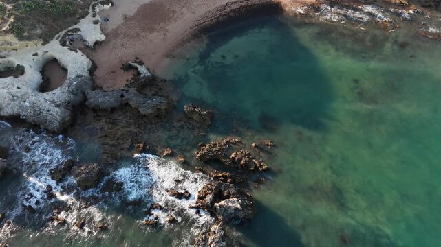 serene rock formations in a coastal beach aerial shot with brown and green tones and water nearby, a natural and peaceful landscape view from above, a tranquil scene of nature's beauty.