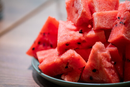 Fresh watermelon pieces on plate on wooden table. Ripe juicy fruit slices for healthy summer snack. Natural organic food and vitamin dessert concept.