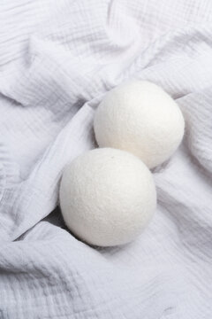 Wool laundry dryer balls placed on a soft white fabric background, showcasing their round shape and texture, ideal for eco-friendly laundry solutions and fabric care