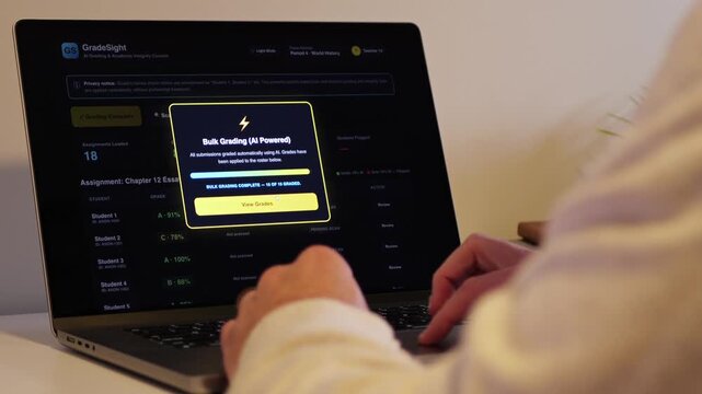 Educator at a laptop using AI software for automated bulk grading of student essays while scanning for unauthorized student AI usage and plagiarism