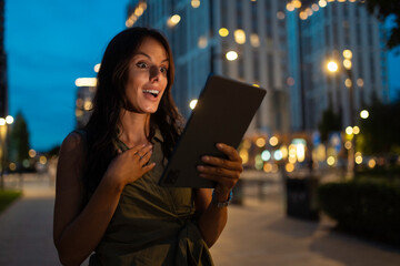 Woman expressing surprise holding tablet at night © Dexon Dee