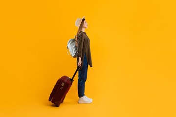 Naklejka premium Focused Young Caucasian Female With Backpack And Rolling Suitcase Preparing For Travel, Standing On Studio Yellow Background. Weight Loss Concept.