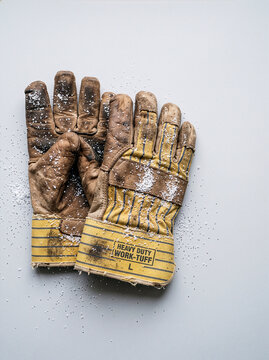 Work Gloves for Labor: A pair of worn, heavy-duty work gloves, showing signs of extensive use, lie on a neutral surface, ready for demanding tasks.