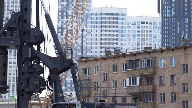 Heavy piling rig standing at an urban construction site surrounded by residential buildings, illustrating deep foundation engineering, bored pile construction and large scale city redevelopment