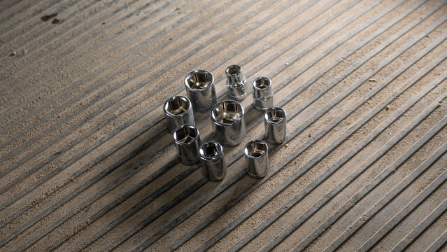 socket wrench set arranged on hardwood floor in indoor setting with neutral mood and top-down viewpoint for home improvement and mechanical tools use cases in modern design.