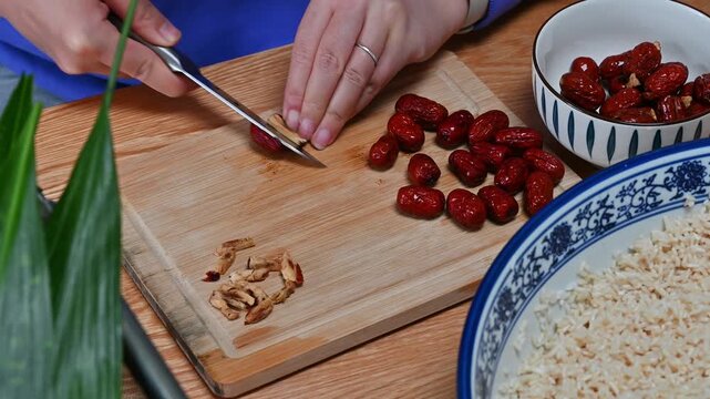 Chinese woman preparing jujubes for zongzi rice dumplings in kitchen