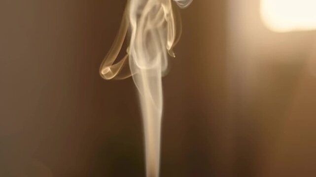 Elegant white smoke plume rising gracefully against warm blurry background in cinematic motion footage showcasing soft ethereal swirling artistic effects