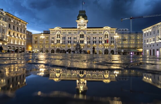 Illuminated square Piazza Unit&agrave; d'Italia, Town Hall, Palazzo Communale, with reflection, dramatic clouds, blue hour, old town, Trieste, Friuli-Venezia Giulia region, Italy