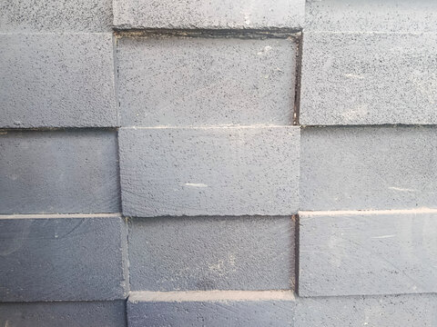 Close-up view of a gray brick wall with rough textured surfaces, visible mortar lines, and subtle variations in tone. Suitable for architecture, construction, industrial design, urban backgrounds, and