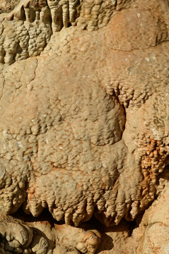 Flowstone, a type of cave formation created by thin sheets of mineral-rich water flowing down walls or floors.Formation: Water carrying dissolved minerals, usually calcite, 