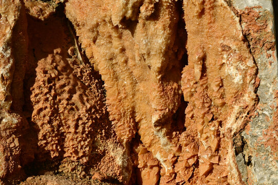 A  close-up, rough geological formation with crystalline mineral deposits, resembling a cave wall or mineral crust.
