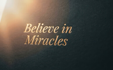 Fototapeta premium Believe in Miracles gold text embossed on dark textured paper inspirational quote for motivation and hope graphic design concepts