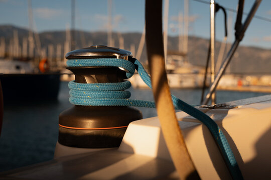 Detailed close-up of a classic sailing yacht winch with coiled ropes in marina during sunset