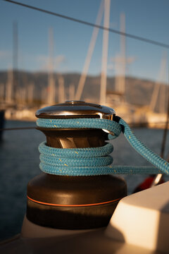Detailed close-up of a classic sailing yacht winch with coiled ropes in marina during sunset