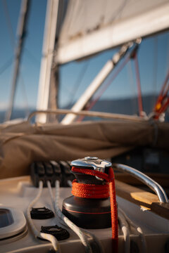 Close-up of active sailing yacht winch with coiled halyard and full sails in background