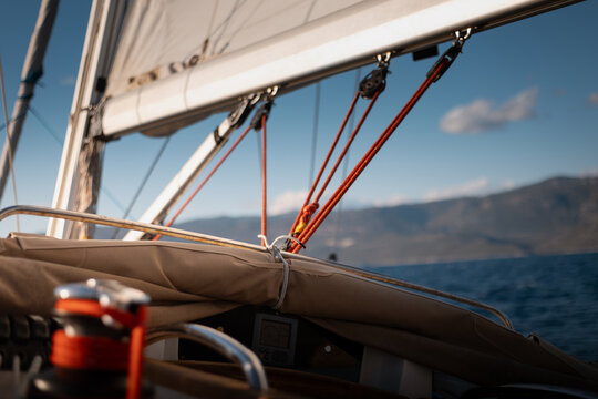 Close-up of active sailing yacht winch with coiled halyard and full sails in background