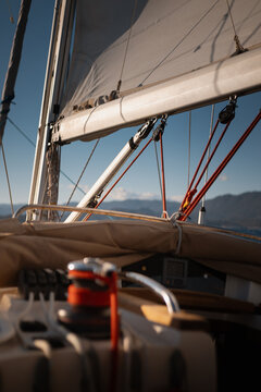 Close-up of active sailing yacht winch with coiled halyard and full sails in background