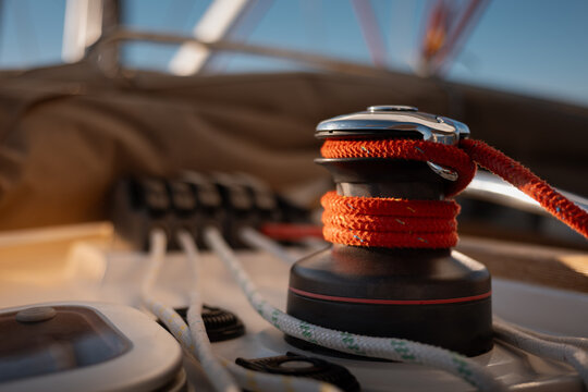 Close-up of active sailing yacht winch with coiled halyard and full sails in background