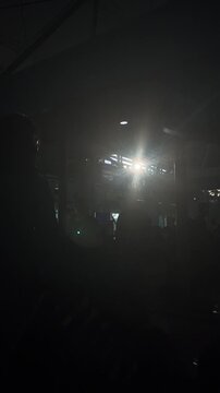 Dimly lit indoor space with bright light source and silhouettes