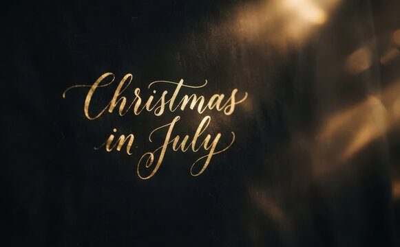 Elegant Christmas in July calligraphy lettering design with gold typography on black background for seasonal holiday greeting card concepts