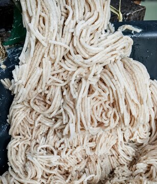 Fresh minced snakehead fish paste during the industrial grinding and shaping process resembling noodles