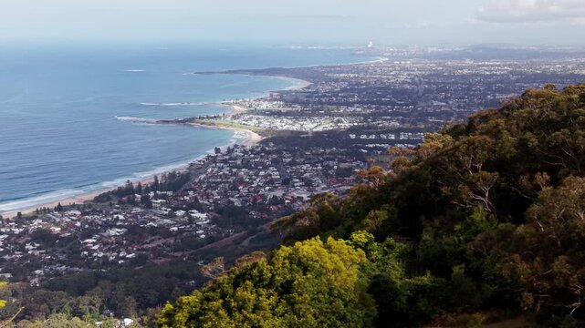 Cinematic drone view of Wollongong city skyline with mountain escarpment foreground, parallax effect 
