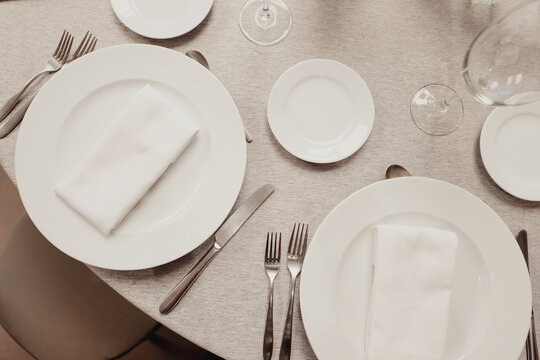 Overhead view of an elegant table setting with white plates, cutlery and glassware prepared for a formal meal or celebration.