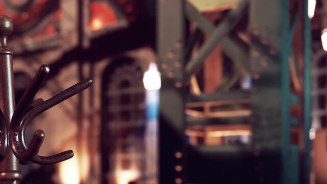 A metal hook stand is in focus while an industrial style environment fills the background. Warm lights highlight the textures of the walls and structures.