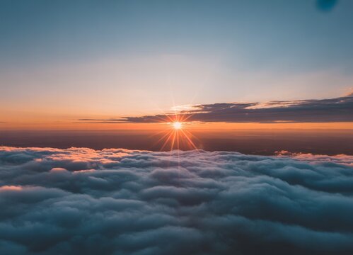 Sunburst over a thick blanket of clouds at sunset view from high altitude with golden hour beauty in nature sun rays cloud layer sunburst