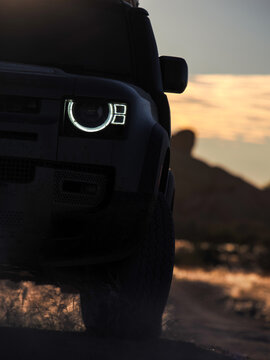 Off-road SUV headlight driving at sunset, copy space