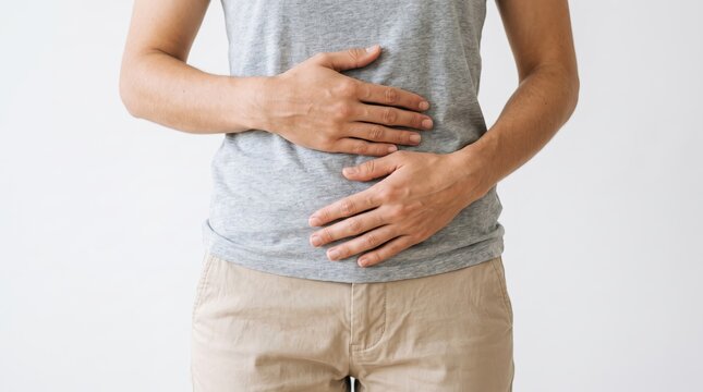 Young man holding stomach in pain, suffering from abdominal cramps, acid reflux, or digestive issues, representing health problems, illness, gastroenteritis, food poisoning