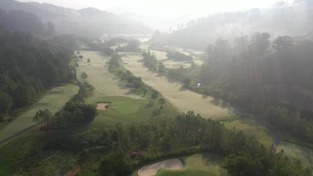 Aerial drone view of SAM Tuyen Lam Golf Club in Da Lat, Vietnam, showcasing lush fairways surrounded by pine forests and mountain scenery in the scenic Tuyen Lam Lake area.