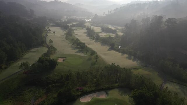 Aerial drone view of SAM Tuyen Lam Golf Club in Da Lat, Vietnam, showcasing lush fairways surrounded by pine forests and mountain scenery in the scenic Tuyen Lam Lake area.