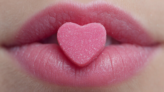 pink matte heart shape gummie inside beautiful woman lips