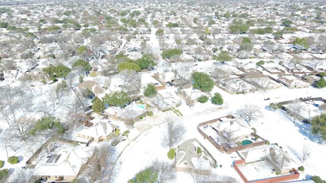 Residential cul de sacs branch from East Sandy Lake Road across DFW metropolitan area. Crisp white snowpack covers winding suburban roadways, single family rooflines in Coppell, Texas