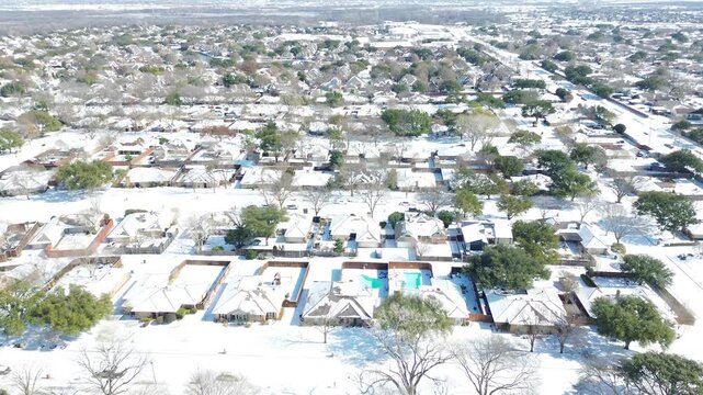 Subdivision housing blocks flank Moore Road near Grapevine Springs Park in DFW metroplex. Dense snowdrifts coat residential rooftops, fenced backyards, dormant hardwoods in Coppell, Texas