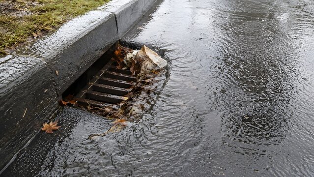 Clogged storm drain causing street flooding after heavy rain